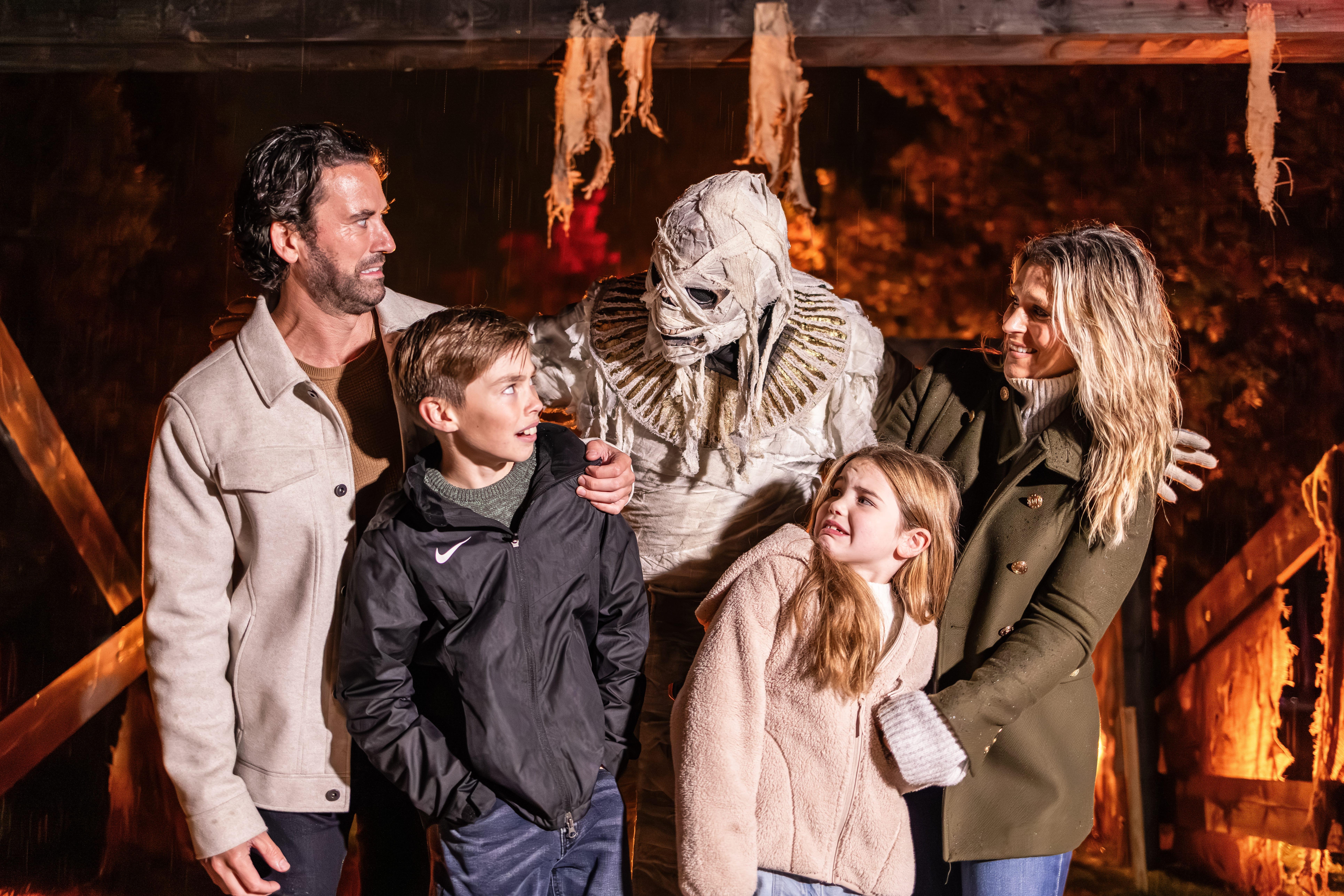 A family meeting a costumed mummy character at a Halloween attraction at night
