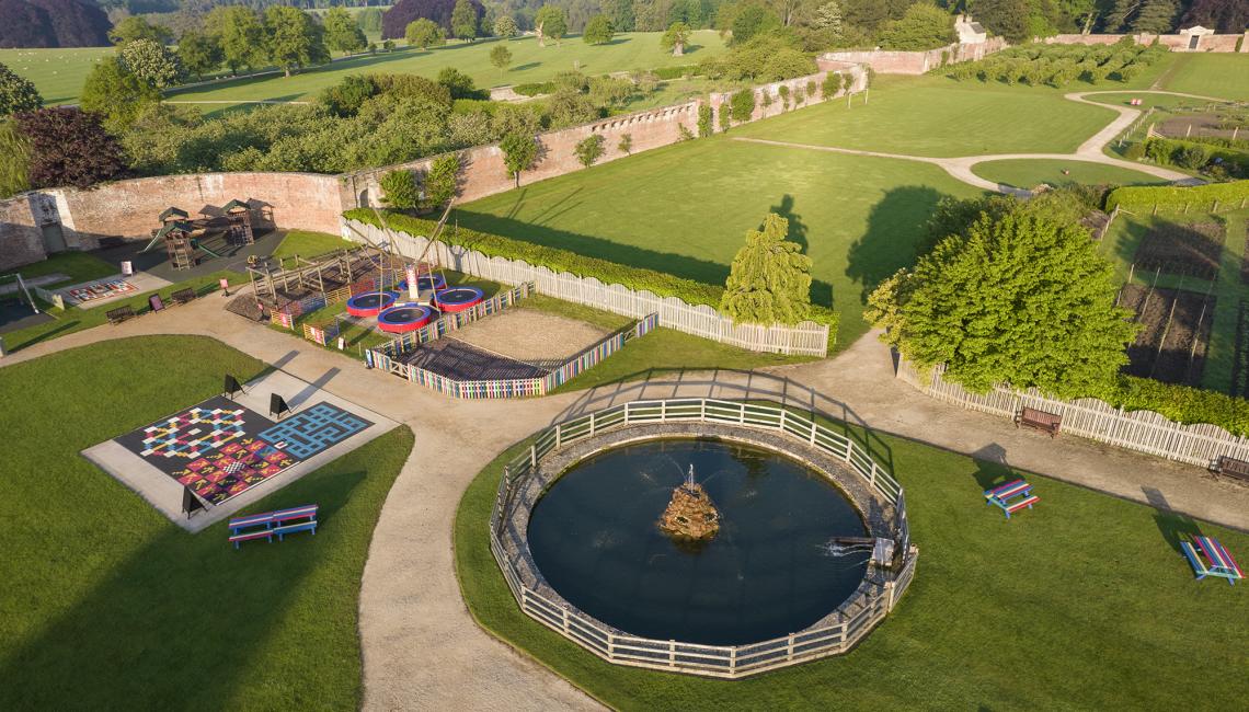 An aerial view of the walled garden play area with lawn games, trampolines and a circular pond