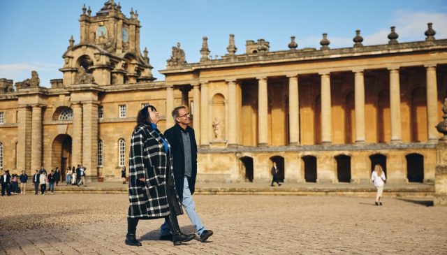 Two visitors walking across the Great Court beside the Palace colonnade