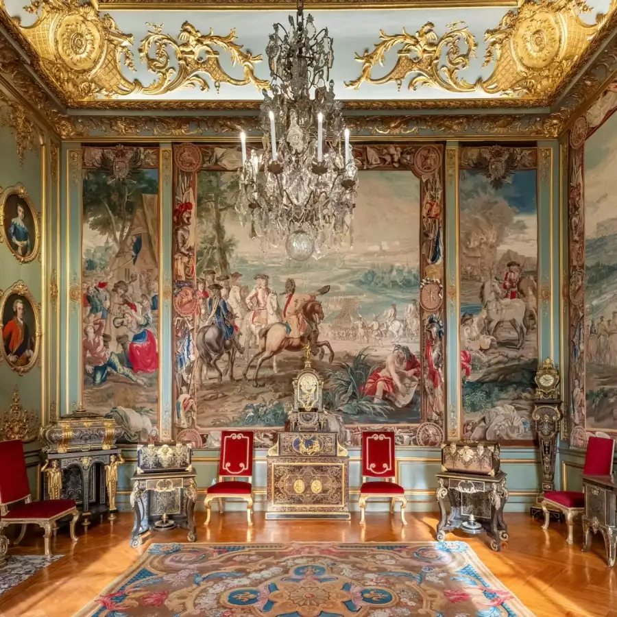 A State Room hung with the Marlborough tapestries, with gilt and red chairs beneath a chandelier