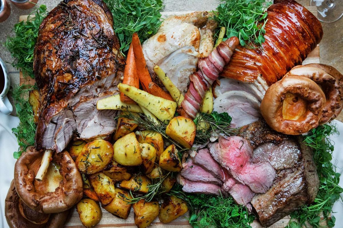 A sharing board of roast meats with potatoes, root vegetables and Yorkshire puddings