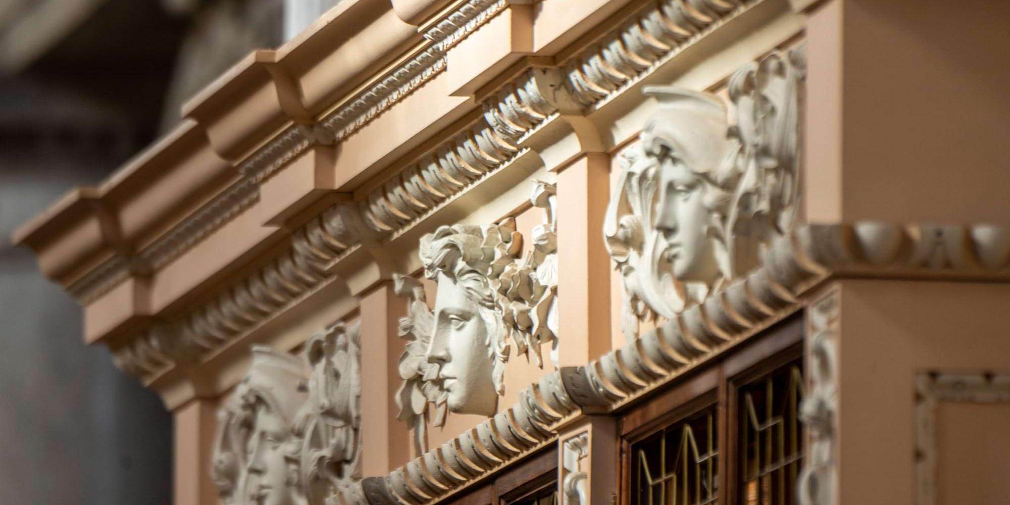 Carved classical masks decorating the cornice above the library bookcases