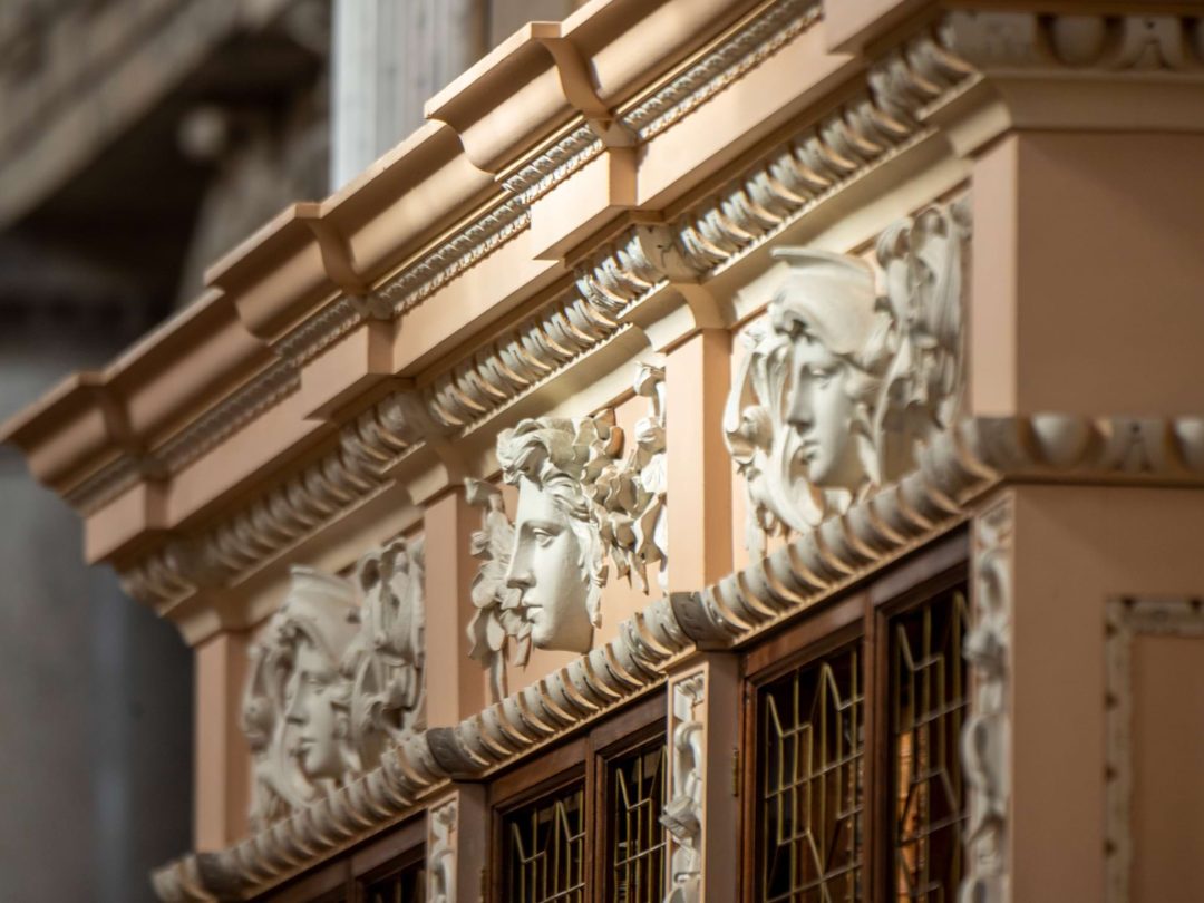 Carved classical masks decorating the cornice above the library bookcases