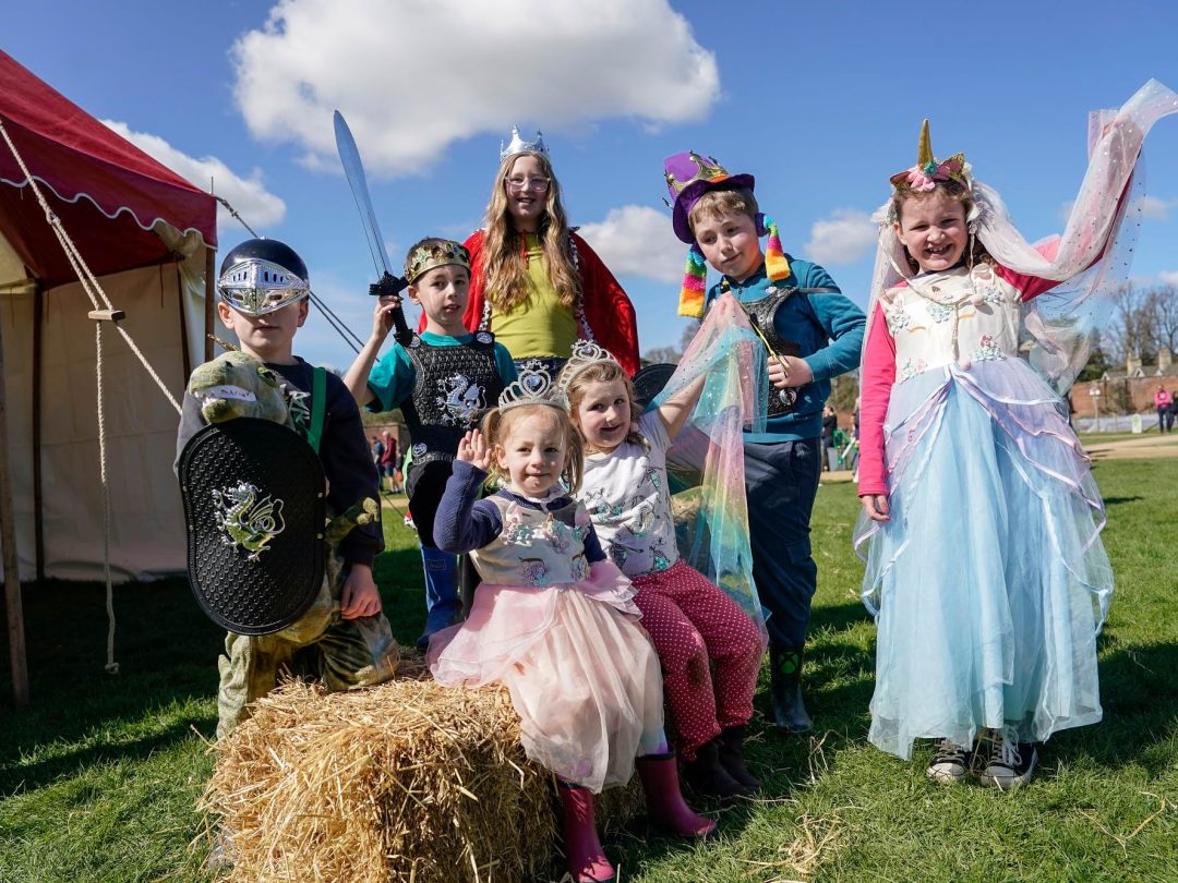 Children dressed as knights and princesses beside a striped marquee