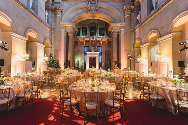 The Great Hall set with round tables for a banquet beneath its arches