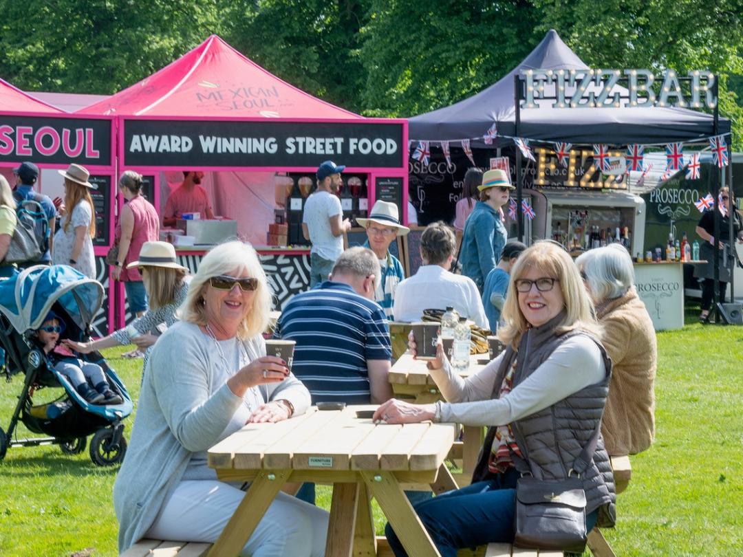 Visitors at picnic tables in front of street food stalls at the food festival