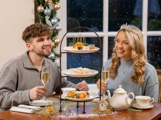 A festive afternoon tea stand of sandwiches, scones and cakes among Christmas decorations