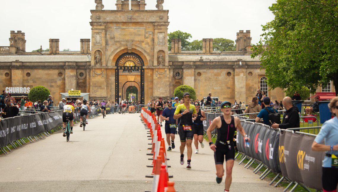 Triathlon runners on the course beside the Palace, with the gateway arch behind