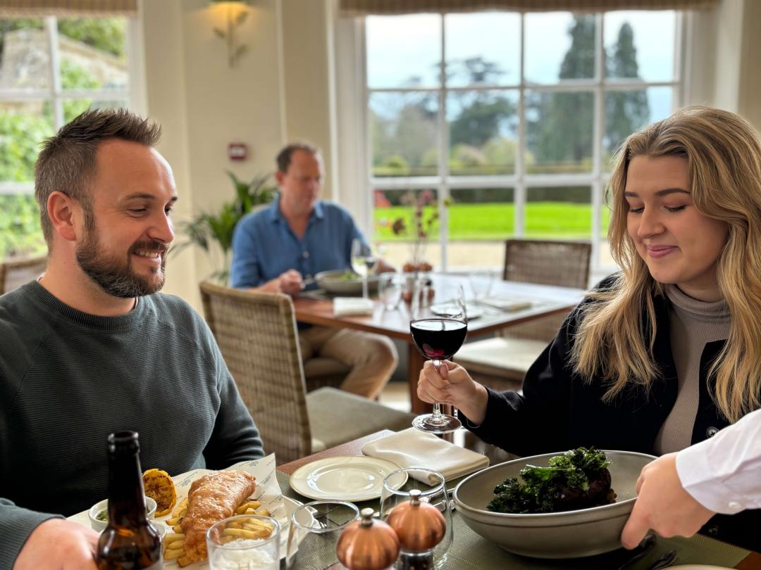 Two diners at a window table in the Orangery restaurant as a dish is served