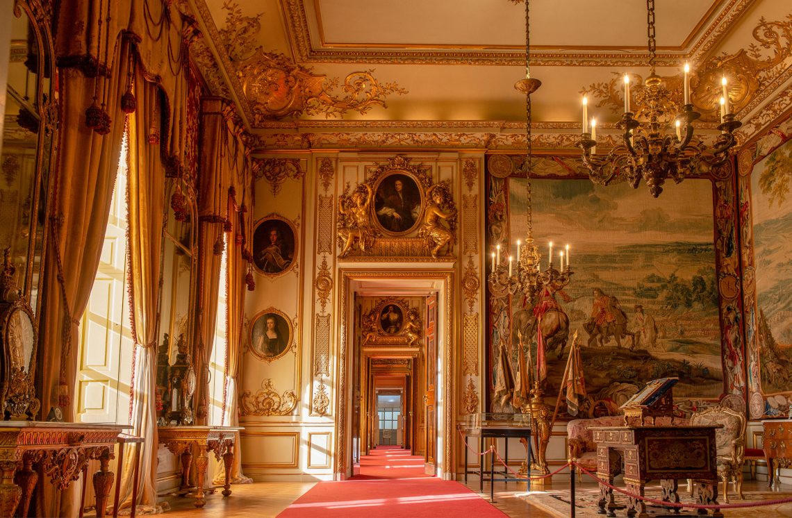 A State Room with tapestries and a chandelier, looking through the doorways towards the red carpet runner