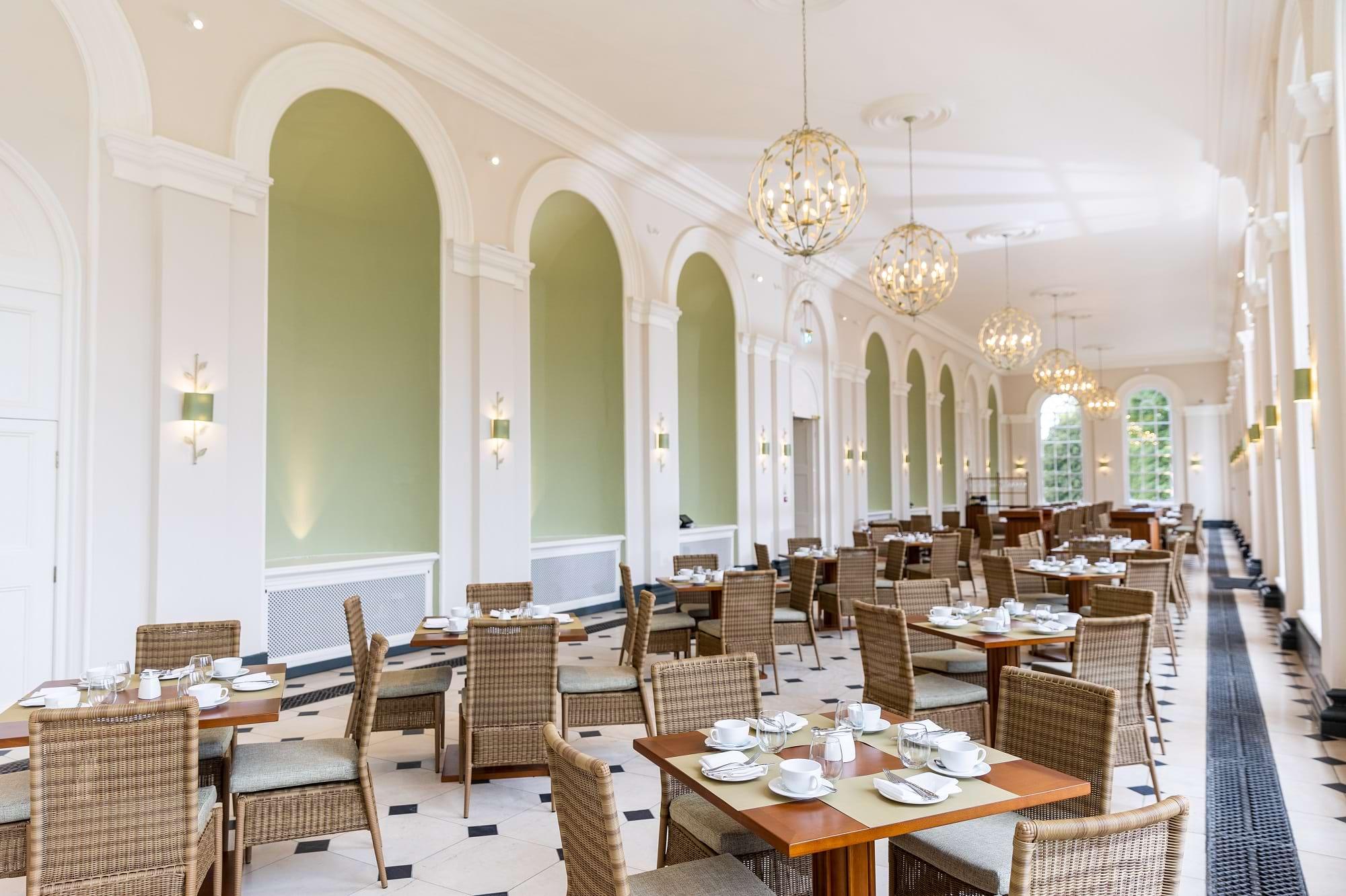 The Orangery restaurant laid for service, with green alcoves and globe chandeliers