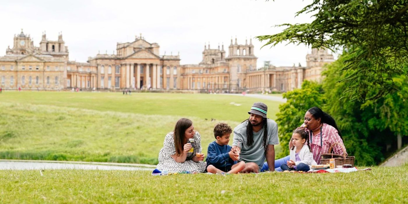 A family picnicking on the lawn with Blenheim Palace behind them