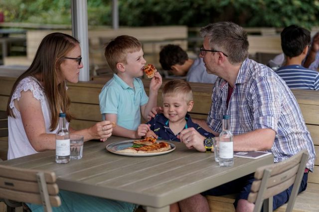 A family sharing a pizza at an outdoor table at the Pizza Cafe