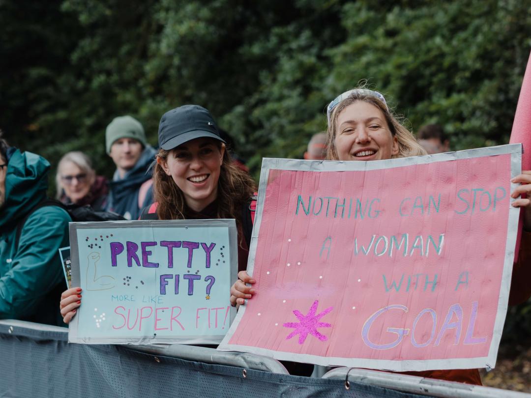 Two spectators holding handmade signs cheering on triathlon competitors