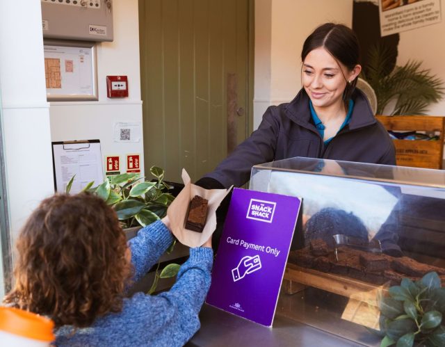 A member of staff handing a brownie to a child at the Snack Shack kiosk