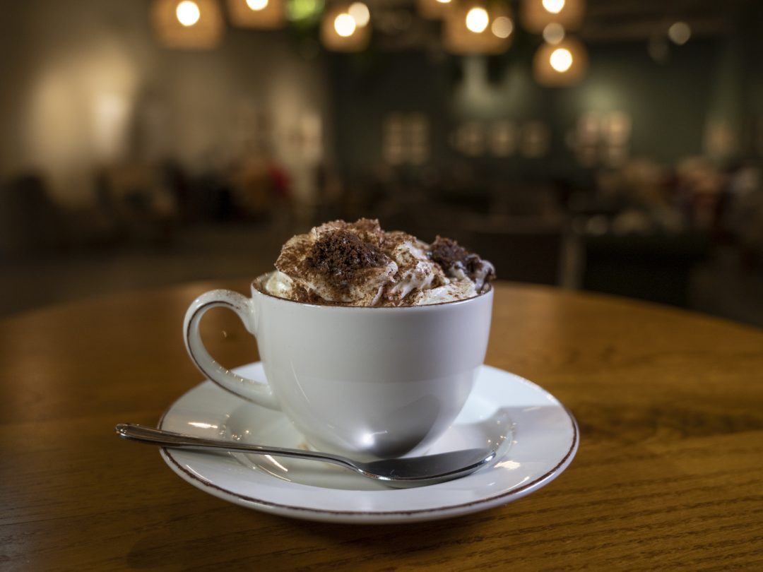 A cup of hot chocolate topped with whipped cream and grated chocolate on a cafe table