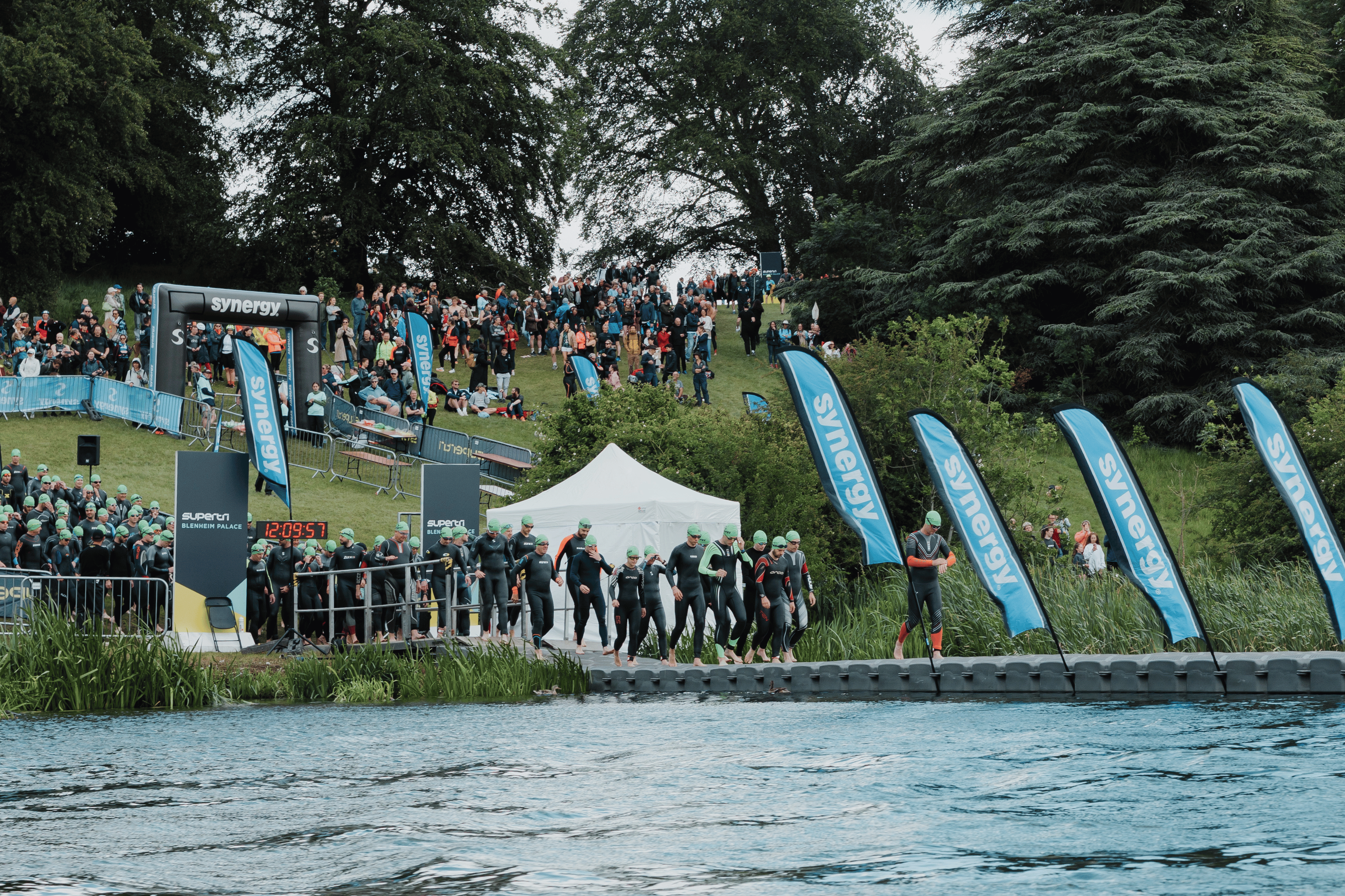 Competitors entering the lake at the triathlon swim start, watched by spectators