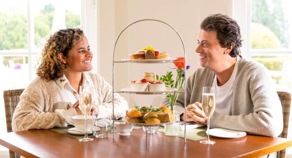 A couple sharing afternoon tea and sparkling wine at a window table
