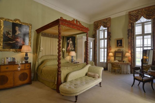 A bedroom on the upstairs tour, with a carved four-poster bed and family portraits