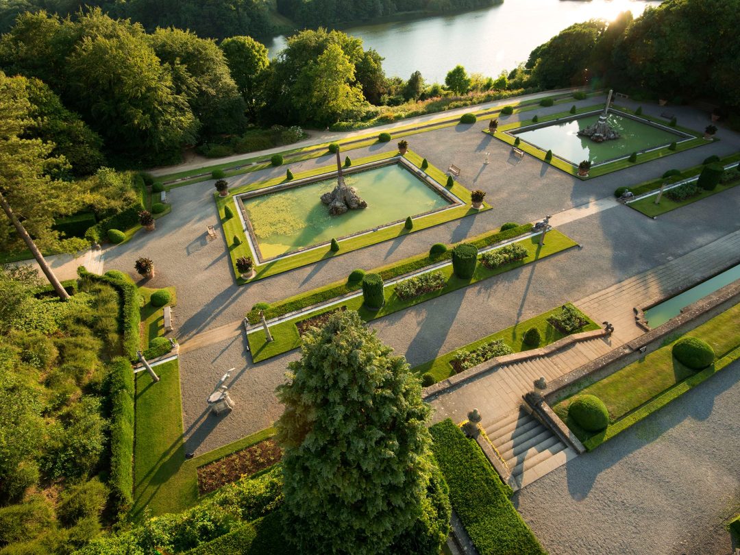 An aerial view of the Water Terraces at Blenheim Palace, with their pools and fountains and the lake beyond