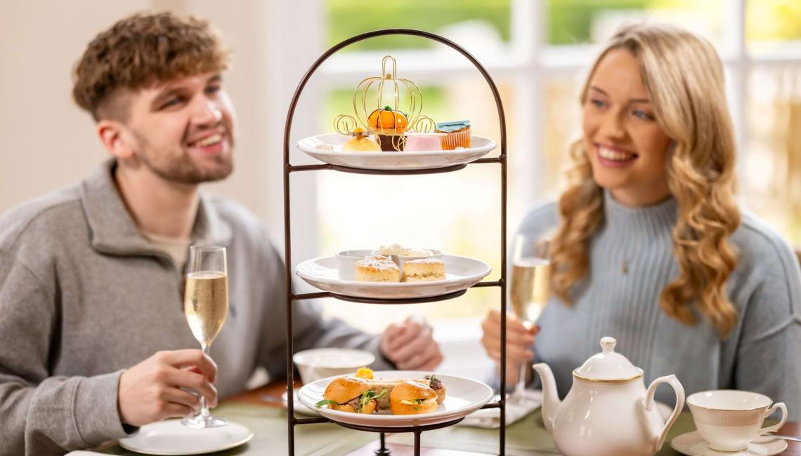 A festive afternoon tea stand of sandwiches, scones and cakes among Christmas decorations