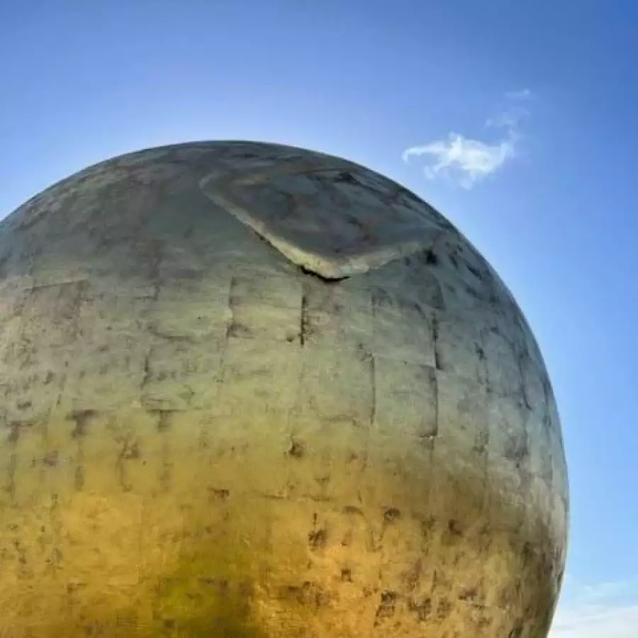 Close-up of a gilded ball with worn, patchy gilding and a dented, split panel